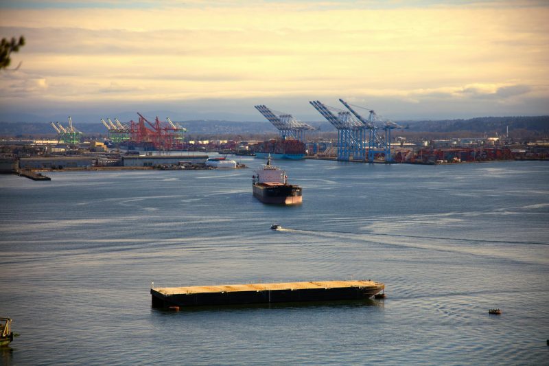 Aerial view of Tacoma Port featuring cargo ships, cranes, and a clear blue sky.