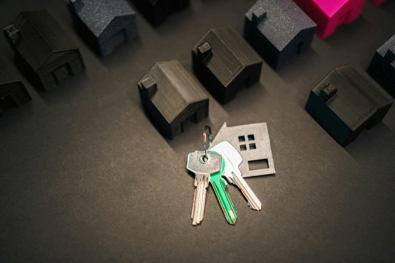 Miniature house models scattered with keys, representing real estate and investment concepts.