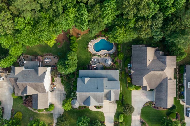 Aerial view of a lush suburban neighborhood with green backyards and a swimming pool in Wake Forest, NC.