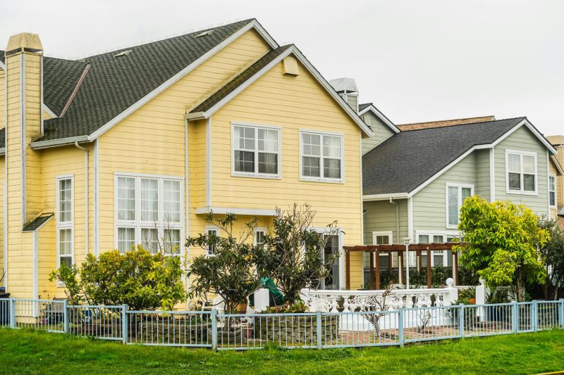 Bright suburban houses with well-maintained gardens and fences in a family-friendly neighborhood.