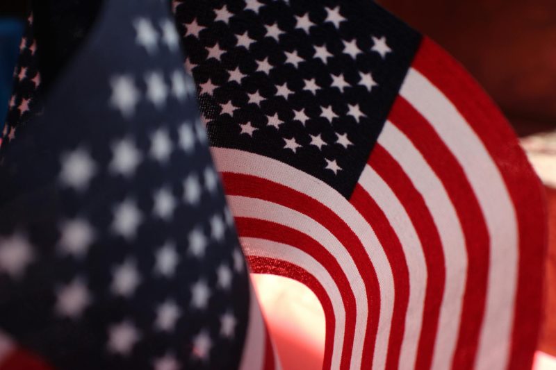 Close-up of an American flag waving, highlighting the stars and stripes against a blurred background.