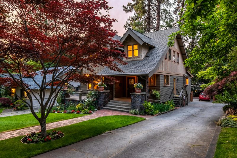 Beautiful suburban house at twilight with elegant landscaping and a striking red maple tree.