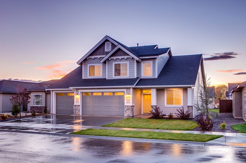 Elegant suburban home with modern architecture and a driveway, set against a vibrant sunset.